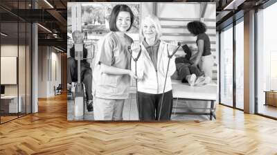 Rehab clinic gym. Elderly man and two women assisted by nurses Wall mural