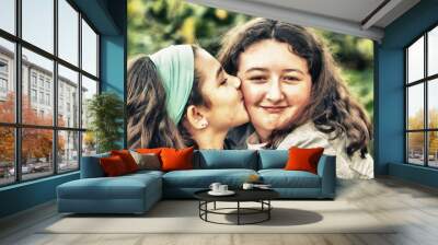 Two young girls embracing and kissing outdoor. Wall mural