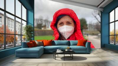 Woman dressed in red on a rainy day outdoor wearing face mask in pandemic time Wall mural