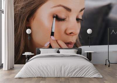 Close up portrait of beautiful young woman applying eyeshadow powder Wall mural