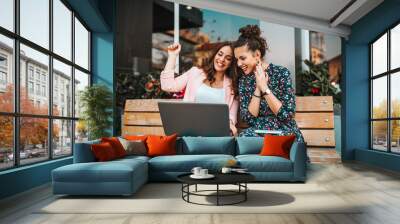 Two female friends elebrating success reading good news in a laptop Wall mural