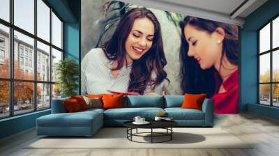 Two women reading paper documents while sitting in the table in a cafe Wall mural