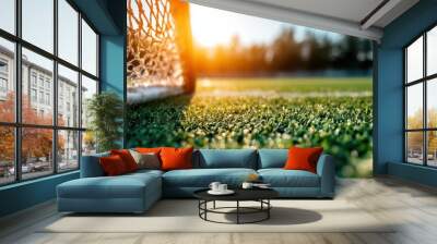 A close-up captures vibrant dewy grass with the warm glow of the sun illuminating a soccer goal net in the background, evoking a sense of freshness and energy. Wall mural