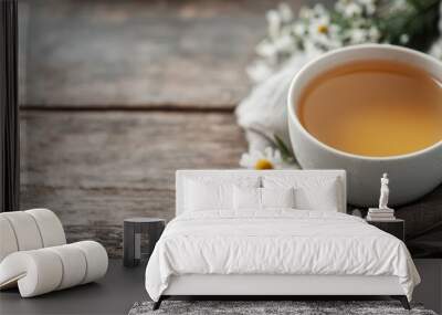 A delightful display of chamomile tea in a white cup, accompanied by a bunch of fresh daisies, all resting on a rustic wooden surface, providing a sense of calm and relaxation. Wall mural