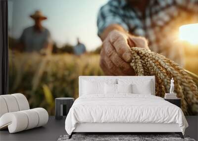 A farmer's hand gently harvests wheat, highlighting ripe grains against the golden backdrop of a sunlit field, reflecting hard work, nature, and abundance. Wall mural