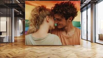 A loving couple stands close under a rainbow flag, symbolizing pride and inclusivity. Their relaxed stance and smiles reflect warmth and acceptance. Wall mural