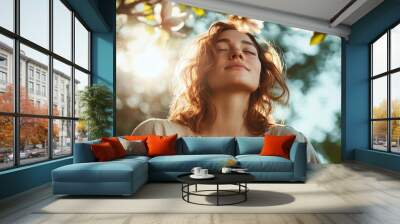 A peaceful young woman enjoys sunlit serenity beneath magnolia blossoms, captured in soft focus conveying a sense of relaxation and rejuvenation outdoors. Wall mural