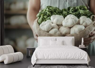 A person holds a burlap bag filled with fresh greens and mushrooms, representing farm-to-table produce and a commitment to sustainable, natural lifestyle choices. Wall mural