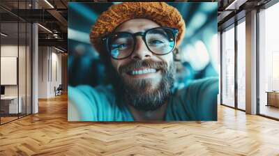 A smiling man with a beard and glasses takes a selfie while traveling on an airplane, radiating happiness and excitement, making for an engaging stock photo for travel concepts. Wall mural