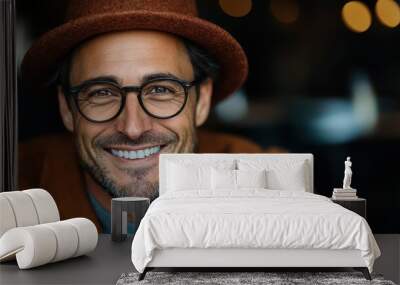 Sporting a brown hat and glasses, a man smiles across a cozy cafe, embodying happiness and a relaxed, contemporary style in a bustling urban setting. Wall mural