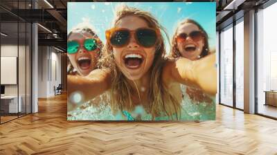 Three joyous young women are captured in a vibrant beach setting, laughing and splashing in the ocean water, exuding a lively and carefree summer spirit. Wall mural