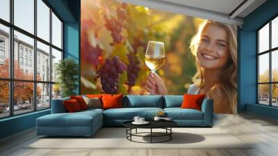 A fashionable beautiful female holding a glass of wine in grape plantation field Wall mural