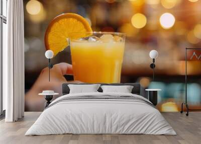 Bar tender holding a glass of juice and fresh orange fruit closeup view on table in a restaurant bar Wall mural