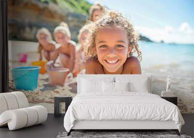 Smiling girl building sandcastles with friends on sunny beach Wall mural