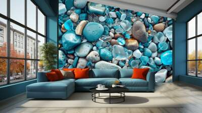 Detailed aerial view of a collection of polished stones and bright blue sea glass on a beach, highlighting natural textures and colors Wall mural