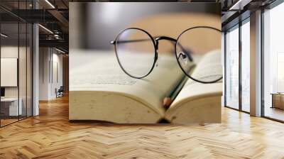 Reading glasses placed on open books Wall mural