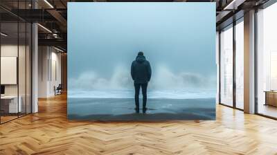 A man stands on a beach in the rain, looking out at the ocean Wall mural