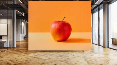 A red apple on an orange background. Wall mural