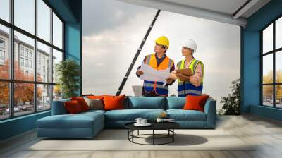 Female engineer and foreman worker checking project at building site, Engineer and builders in hardhats discussing on construction site, Teamwork concepts Wall mural