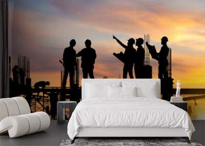 Silhouette of Engineer and worker on building site, construction site at sunset in evening time. Wall mural