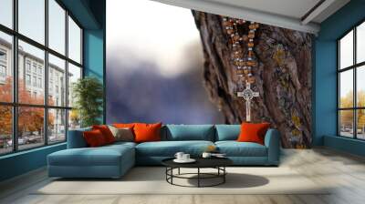 christianity rosary cross hanging on tree trunk, against blurred natural background. easter holiday, Wall mural