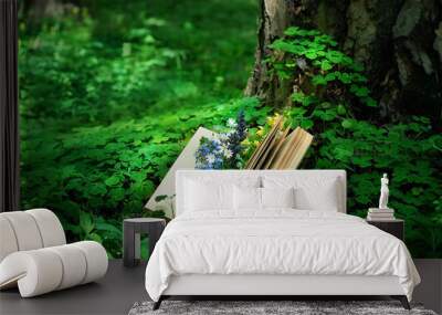 old book and wild flowers in forest, blurred natural green background. romantic inspiration image. Relaxation, Reading, knowledge concept. botany, study of wild herbs and flowers. spring summer season Wall mural