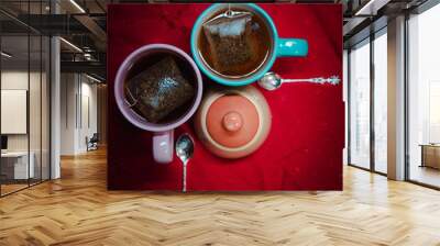 Dos tazas de té y azucarera con cucharas de plata sobre mantel rojo Wall mural