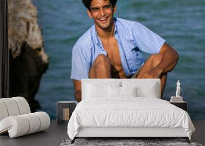 A man sitting on a rock on the beach, at the beach, Margarita Island, Venezuela. Wall mural