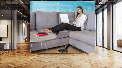 Smiling businesswoman working online on netbook while sitting on couch Wall mural