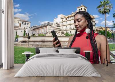 Mujer contenta con su teléfono móvil haciendo turismo en una ciudad europea de vacaciones. Wall mural