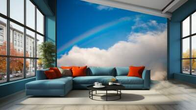 Rainbow in blue cloudy sky Wall mural