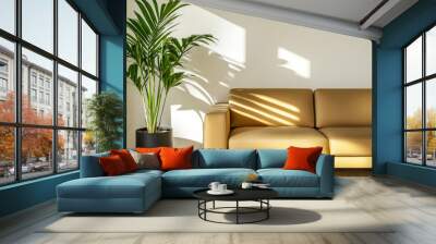 A cozy living room with a modern tan sofa and a potted plant casting shadows in natural light Wall mural