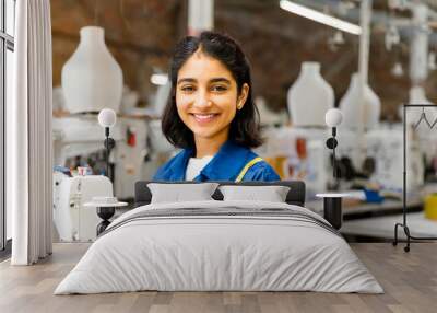 Asian female working. Asian indian seamstress with headscarf in textile factory sewing with industrial sewing machine. Wall mural