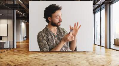 Young queer latin gay man showing how he paints his nails on camera on a white background. Wall mural