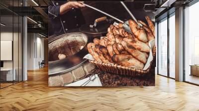 Baker making turkish pita bread in tandoor (clay oven). Baking process. Many fresh hot bread in the basket Wall mural