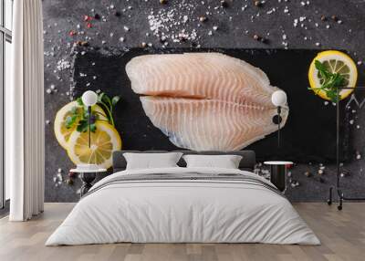 Fresh raw fillet white fish Pangasius with spices and lemon on dark stone background.  Seafood, top view, flat lay, copy space Wall mural