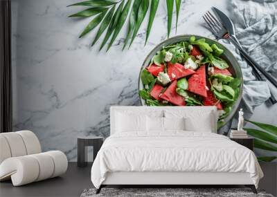 Fresh summer watermelon salad with feta cheese, arugula, spinach and greens on light marble background with tropical leaves. Healthy food, clean eating, Buddha bowl salad, top view Wall mural