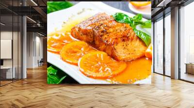 Honey Glazed fillet salmon with orange slices, spices and basil on white plate on dark background. Delicious dish of seafood Wall mural