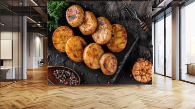 Tasty grilled potatoes with spices on a black rock, dark background, top view. Barbecue concept food, vegan Wall mural