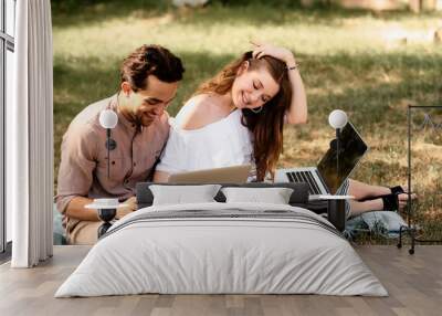 a beautiful teen couple man and women working use laptop to working at outdoor park holiday Wall mural