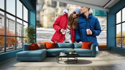 A trendy young couple walks in the city at christmastime Wall mural