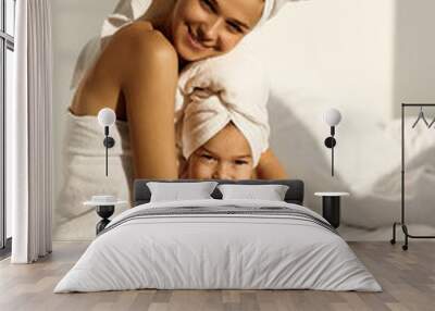 A young caucasian woman with his daughter on a bed at home in the morning, wearing in towel Wall mural