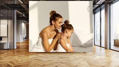 A young caucasian woman with his daughter on a bed at home in the morning, wearing in towel Wall mural