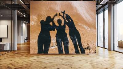 Summer fun. Shadow of a beautiful family having fun on the beach at sunset by the sea. Wall mural