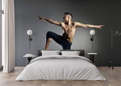 Caucasian man gymnastic leap posture on grey background Wall mural