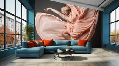 Woman in light chiffon dress dancing sensually on black plain background. Wall mural