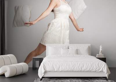 woman in white dress in mid air with flying pillows Wall mural