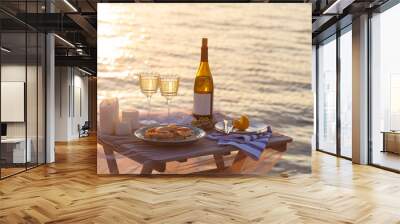 Romantic sunset dinner on the beach. Table honeymoon set for two with luxurious food, glasses of champagne drinks in a restaurant with sea view. Summer love, romance date on vacation concept. Wall mural