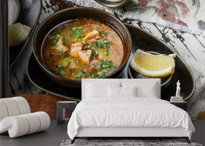 Fish soup with salmon, greens and lemon on bowl on rustic wooden background. Healthy food, top view Wall mural