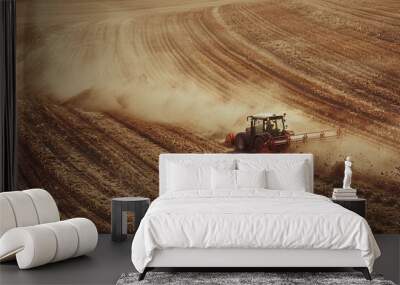 Tractors working on dusty field during autumn harvest season Wall mural